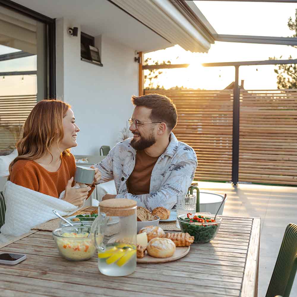 Patio and Sundecks A man and a woman are enjoying a breakfast on their patio with the sun rising over them.